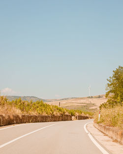 Road passing through landscape against clear sky