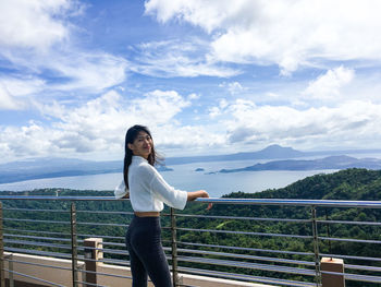 Woman standing by railing against sky