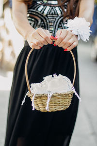 Midsection of woman holding basket while standing outdoors