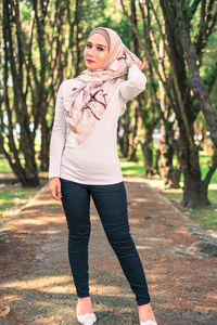 Full length of woman standing against trees