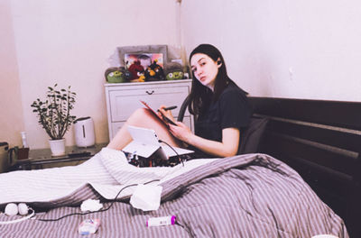 Young woman sitting on book at home