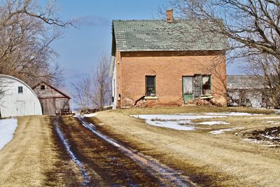 Houses by road against sky during winter