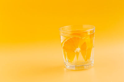 Close-up of beer glass against orange background