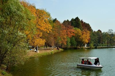 People in boat on river against clear sky