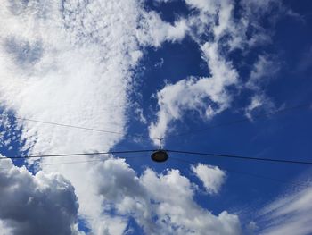 Low angle view of silhouette cables against blue sky