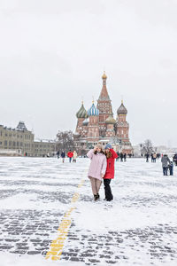 People in front of building against sky during winter