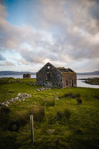 Old building in field against cloudy sky