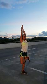 Full length of woman doing yoga on road against sky