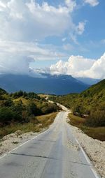 Road leading towards mountains against sky