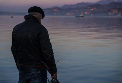 Rear view of man standing in sea against sky