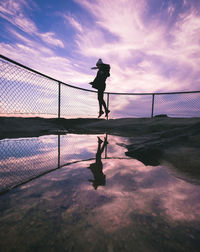 Silhouette man standing on water against sky