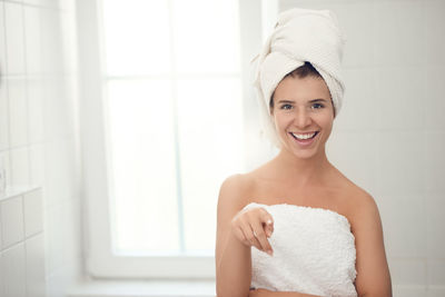 Portrait of smiling young woman pointing in bathroom at home