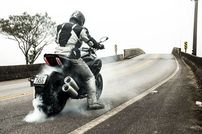 Man riding motorcycle on road against clear sky