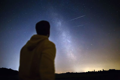 Rear view of man against sky at night