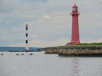 Lighthouse by sea against sky