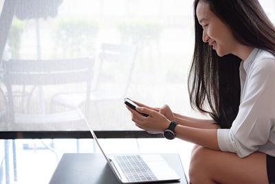 Side view of woman using mobile phone