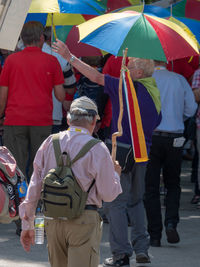 Rear view of people with umbrellas walking on street during parade