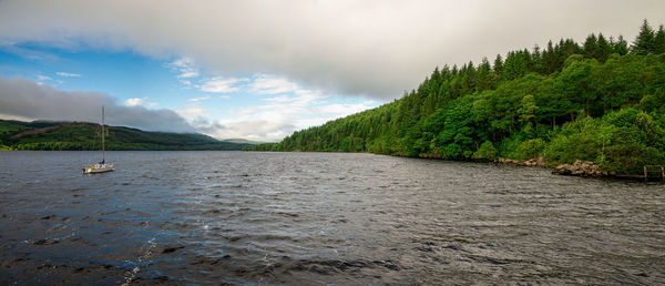 Scenic view of river by mountains against sky