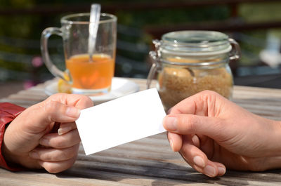 Cropped image of people holding blank tag at table