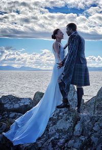 Couple standing by sea against sky