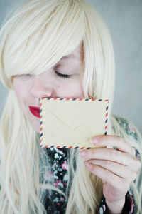 Close-up of smiling young woman smelling envelope