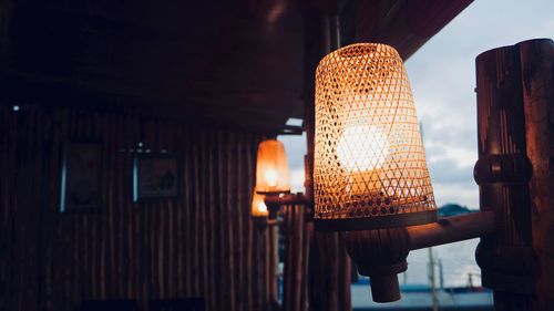 Illuminated lantern by window against sky at dusk