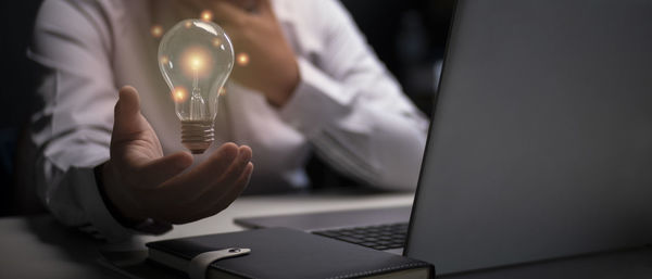 Midsection of woman holding light bulb
