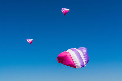 Low angle view of colorful balloons against clear blue sky