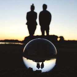 Reflection of people in water at sunset