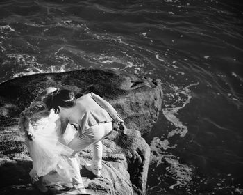 High angle view of bride and groom standing on rock by sea