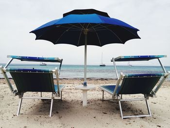 Deck chairs on beach against sky