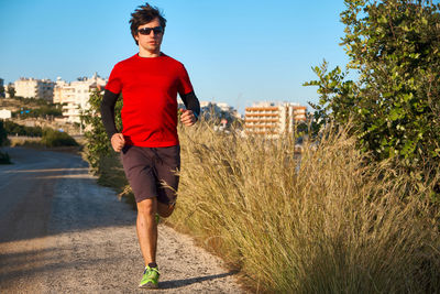 Young man wearing sunglasses on a morning jog in the countryside.