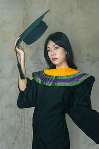 Portrait of young woman standing against wall