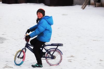 Full length of man riding bicycle on snow