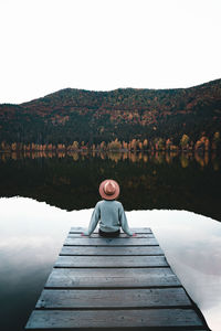 Rear view of woman standing on pier over lake