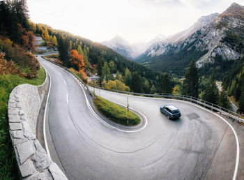 Vehicles on road by mountain against sky