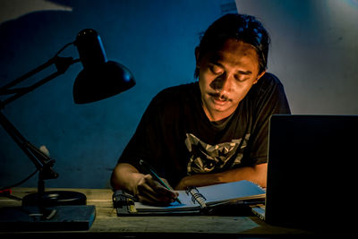 Mid adult man using mobile phone while sitting on table