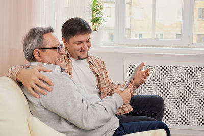 Friends using phone while sitting on sofa at home