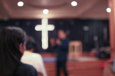 Defocused image of man giving speech to people in church