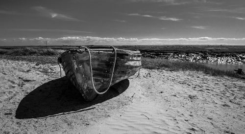 Abandoned boat on beach against sky