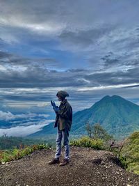 Rear view of man standing on mountain against sky