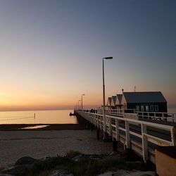 Pier on sea against clear sky during sunset