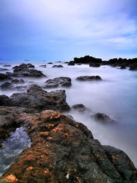 Rocks on sea shore against sky