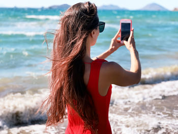 Midsection of woman using mobile phone at beach