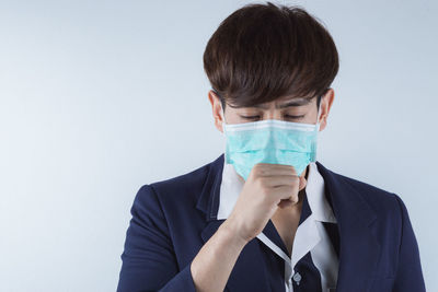 Businessman wearing protective mask against white background