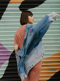 Side view of woman looking away while standing against wall