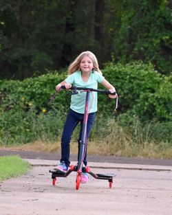 Portrait of girl riding push scooter on road