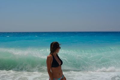 Woman standing at beach against sky