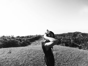 Rear view of woman photographing on landscape against clear sky