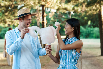 Cheerful couple holding cotton candy outdoors
